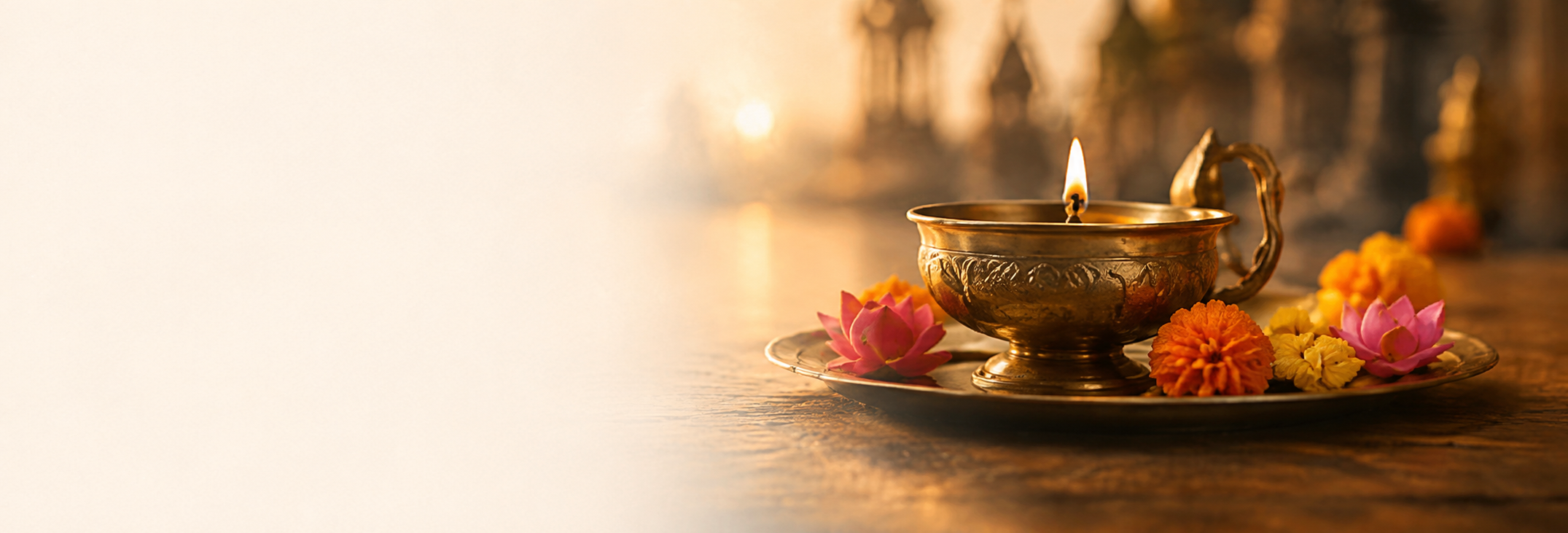 A lit brass diya with marigold and lotus offerings